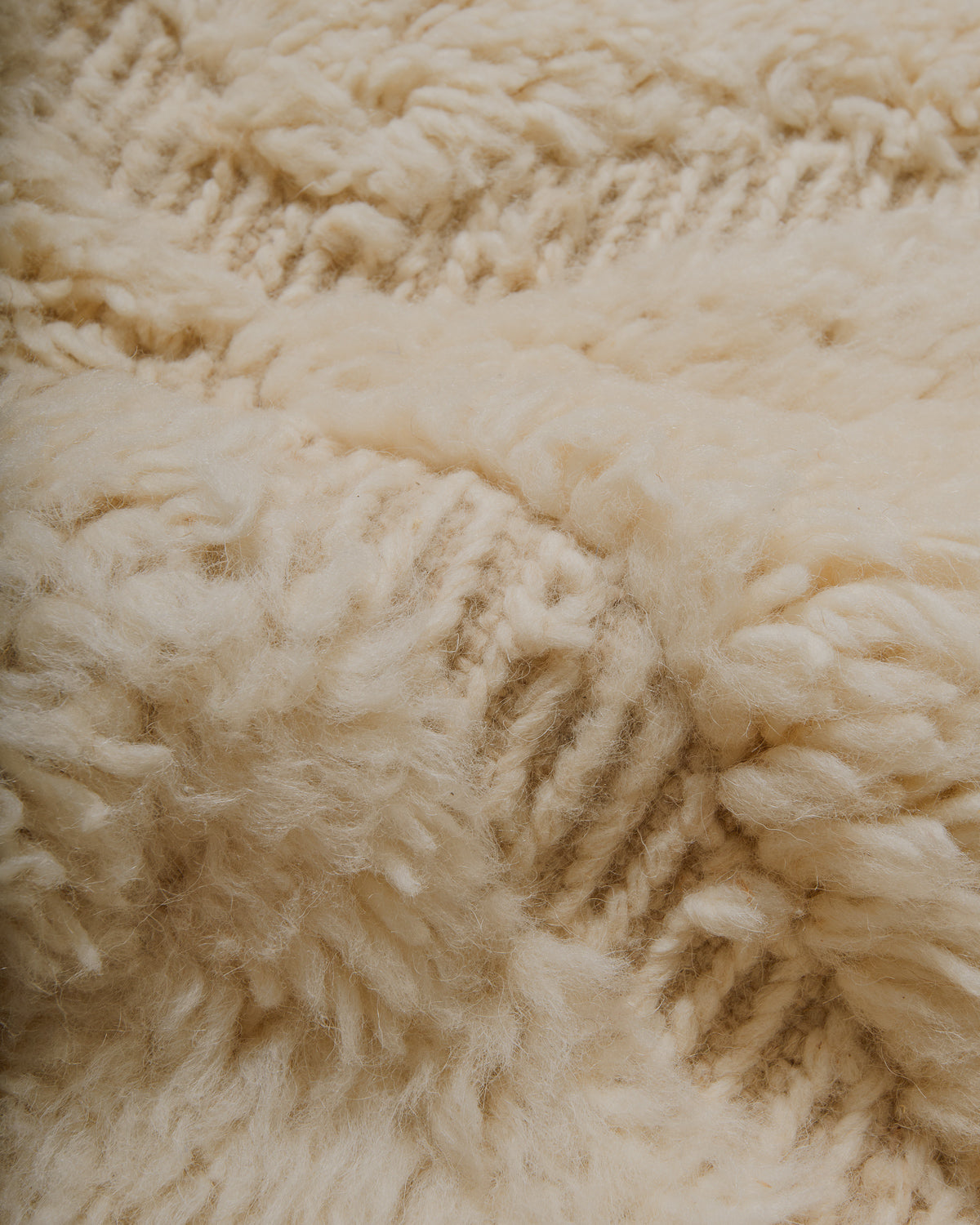 Close-up of cream textured rug with plush pile and flat woven areas.